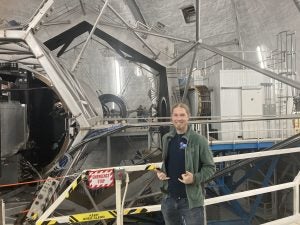 Picture of Tucker at Keck Observatory, standing in front of one of the 10-meter primary mirrors.